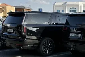 CalibRide professional chauffeur standing beside a black luxury SUV in a grassy field – ready for premium Dubai rides.