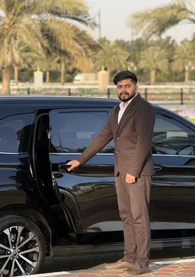 Man relaxing inside a CalibRide luxury car, enjoying the beautiful Dubai desert landscape through the window.